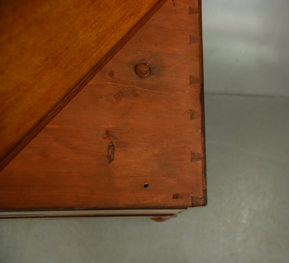 A Victorian mahogany military campaign chest featuring flush recessed brass handles, brass corner mountings, and a two-part construction resting on turned feet. View IX