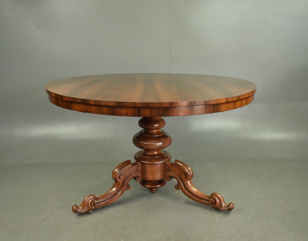 A round Victorian rosewood centre dining table featuring a figured timber top and a carved tripartite pedestal base. View II