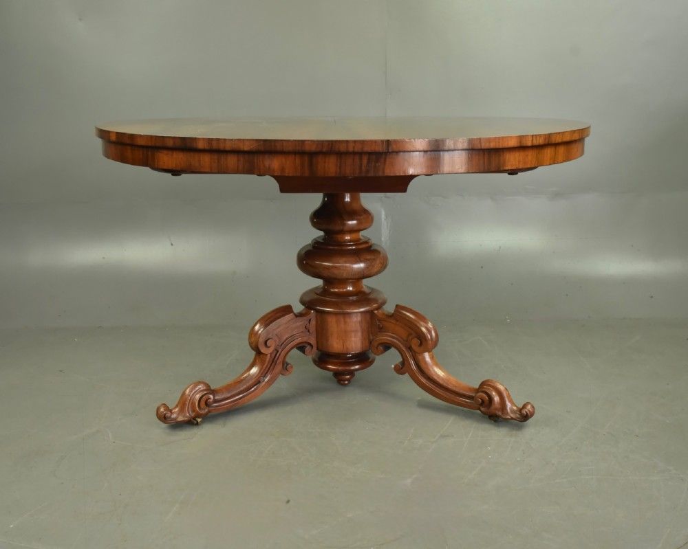 A round Victorian rosewood centre dining table featuring a figured timber top and a carved tripartite pedestal base. View III