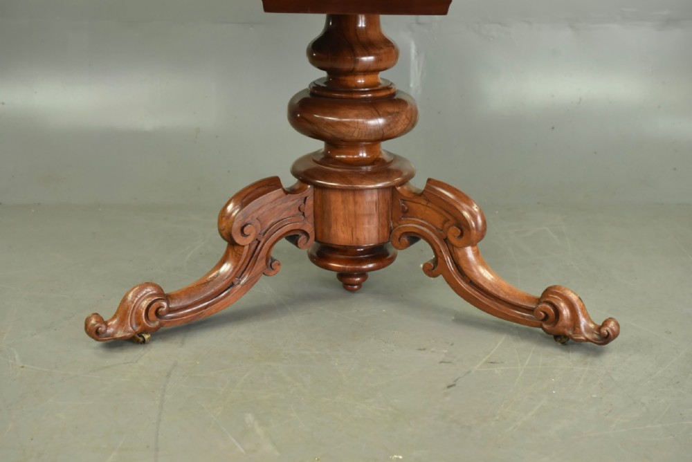 A round Victorian rosewood centre dining table featuring a figured timber top and a carved tripartite pedestal base. View V