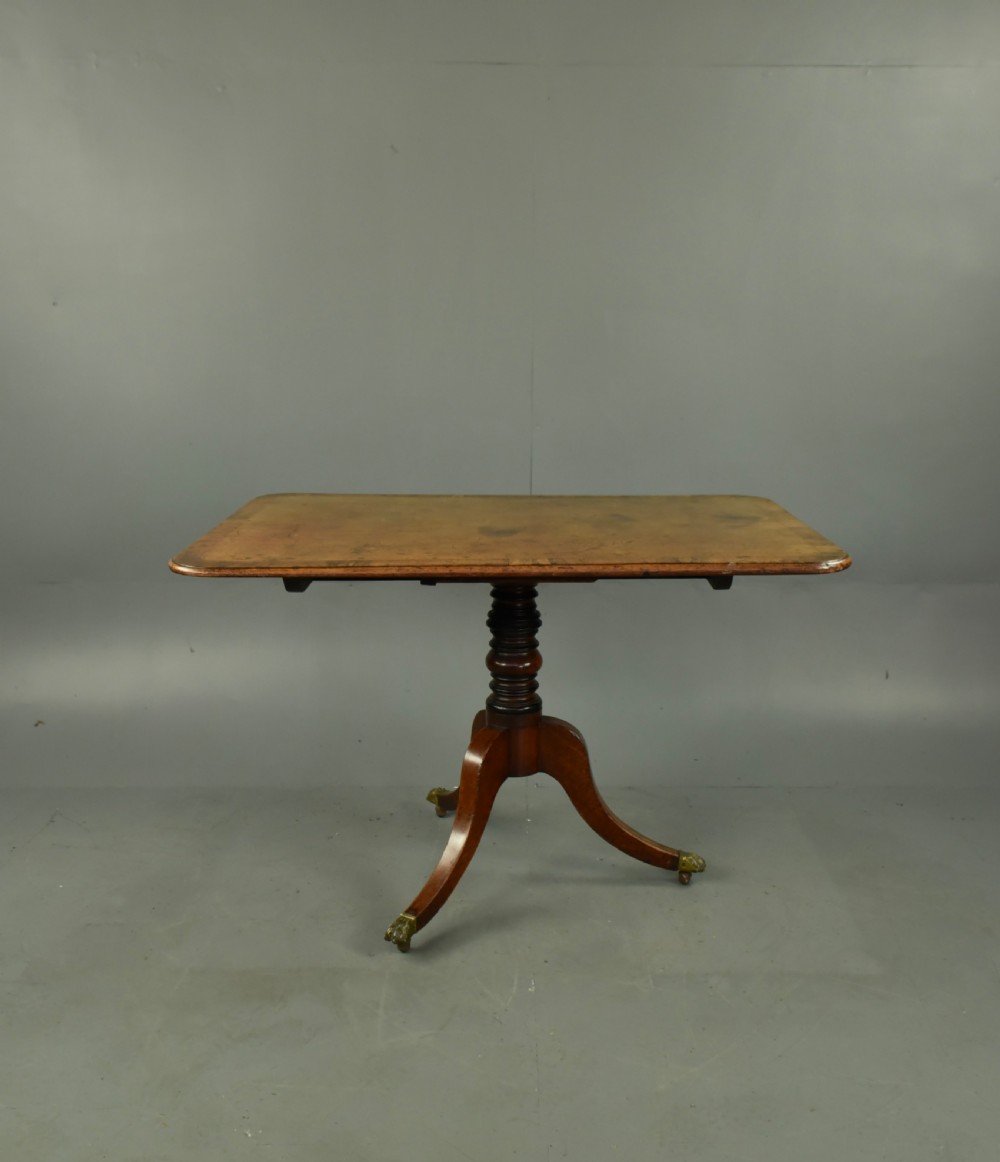 A Georgian mahogany tilt-top supper table with satinwood crossbanding set vertically on a swept tripod base with brass paw feet. View II
