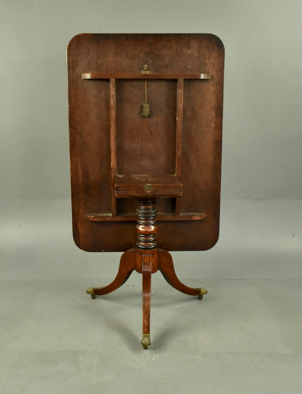 A Georgian mahogany tilt-top supper table with satinwood crossbanding set vertically on a swept tripod base with brass paw feet. View IV