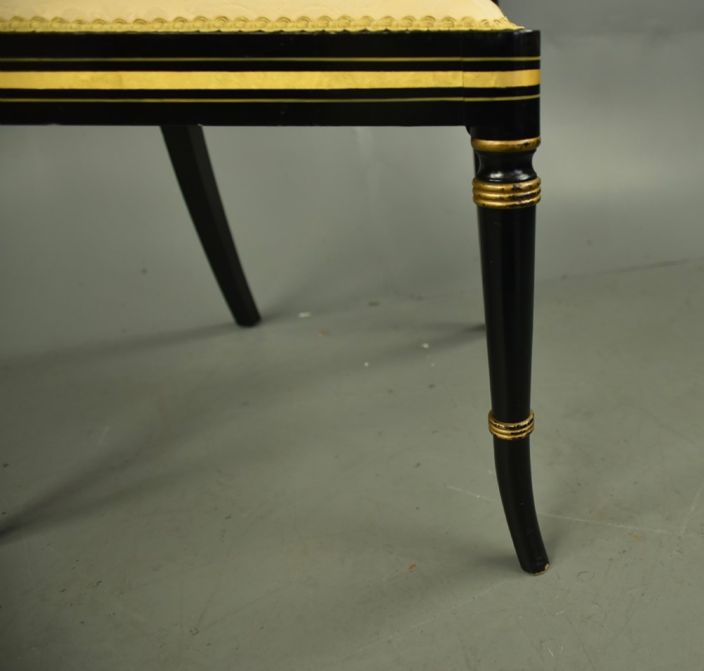 A set of six ebonised Regency dining chairs with gilt line decoration, woven cane back panels, and cream fabric seats. View VI