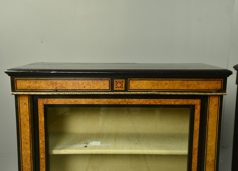 A pair of Victorian ebonised and burr walnut pier cabinets with glass doors, marquetry borders, and internal shelving. View II