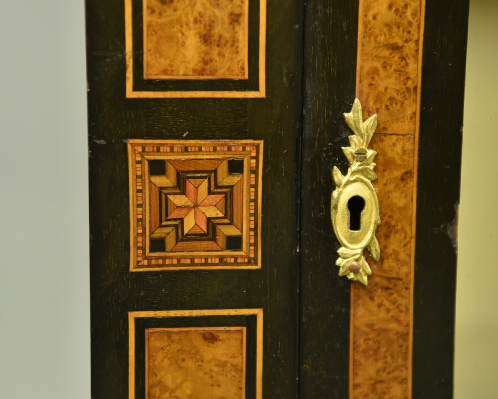 A pair of Victorian ebonised and burr walnut pier cabinets with glass doors, marquetry borders, and internal shelving. View V