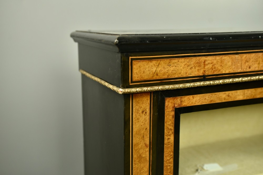 A pair of Victorian ebonised and burr walnut pier cabinets with glass doors, marquetry borders, and internal shelving. View VI