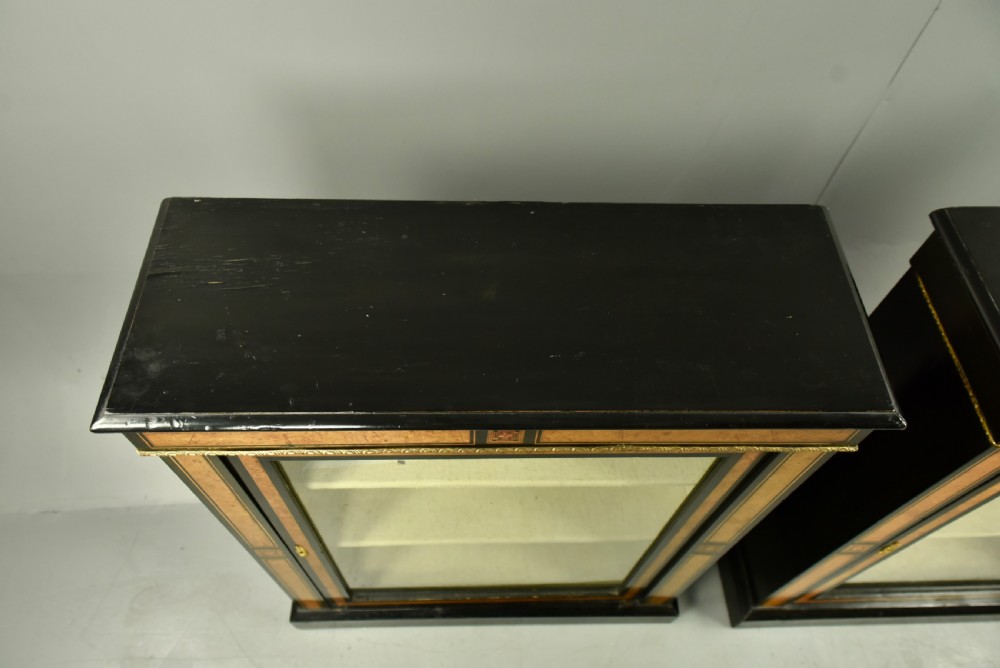 A pair of Victorian ebonised and burr walnut pier cabinets with glass doors, marquetry borders, and internal shelving. View VIII
