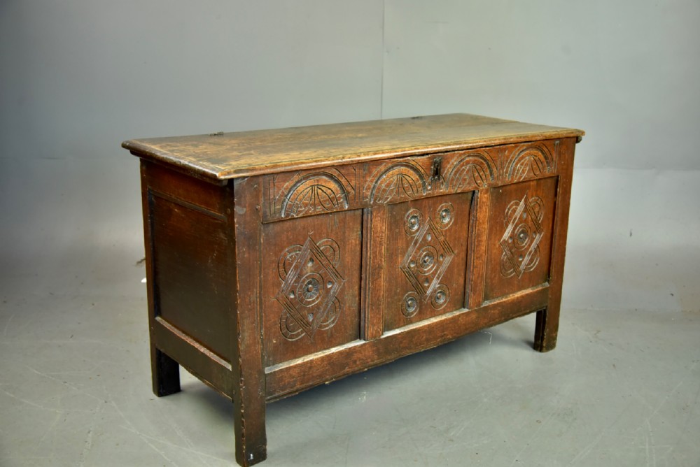 An 18th-century dark oak coffer featuring three carved geometric front panels and a carved lunette frieze resting on stile feet. View III