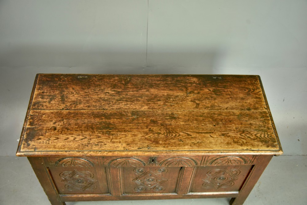 An 18th-century dark oak coffer featuring three carved geometric front panels and a carved lunette frieze resting on stile feet. View IV