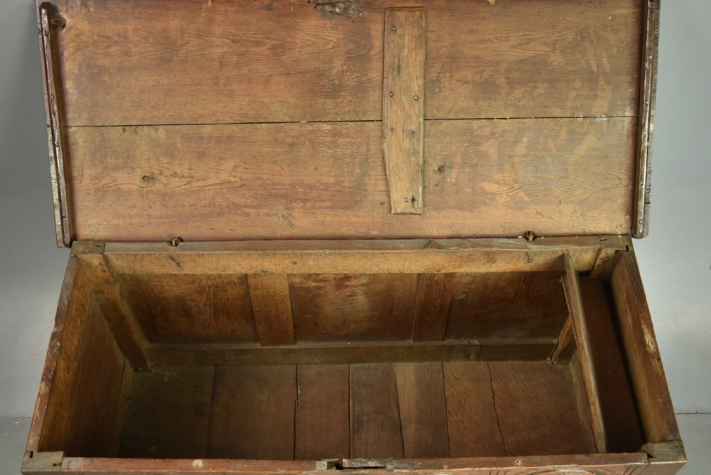 An 18th-century dark oak coffer featuring three carved geometric front panels and a carved lunette frieze resting on stile feet. View VI
