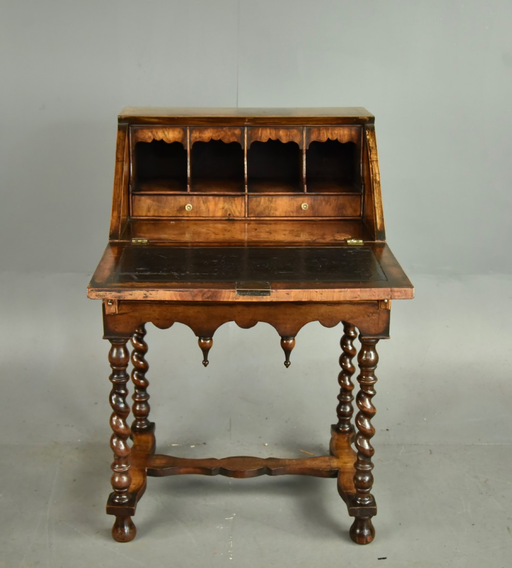 A small walnut bureau featuring an oval floral marquetry panel on the sloped front, set above a drawer and supported by four barley twist legs. View II