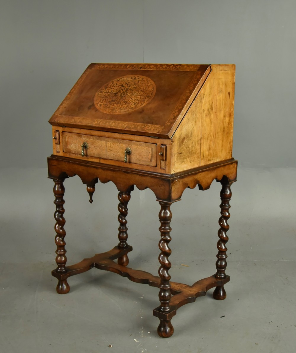 A small walnut bureau featuring an oval floral marquetry panel on the sloped front, set above a drawer and supported by four barley twist legs. View IV
