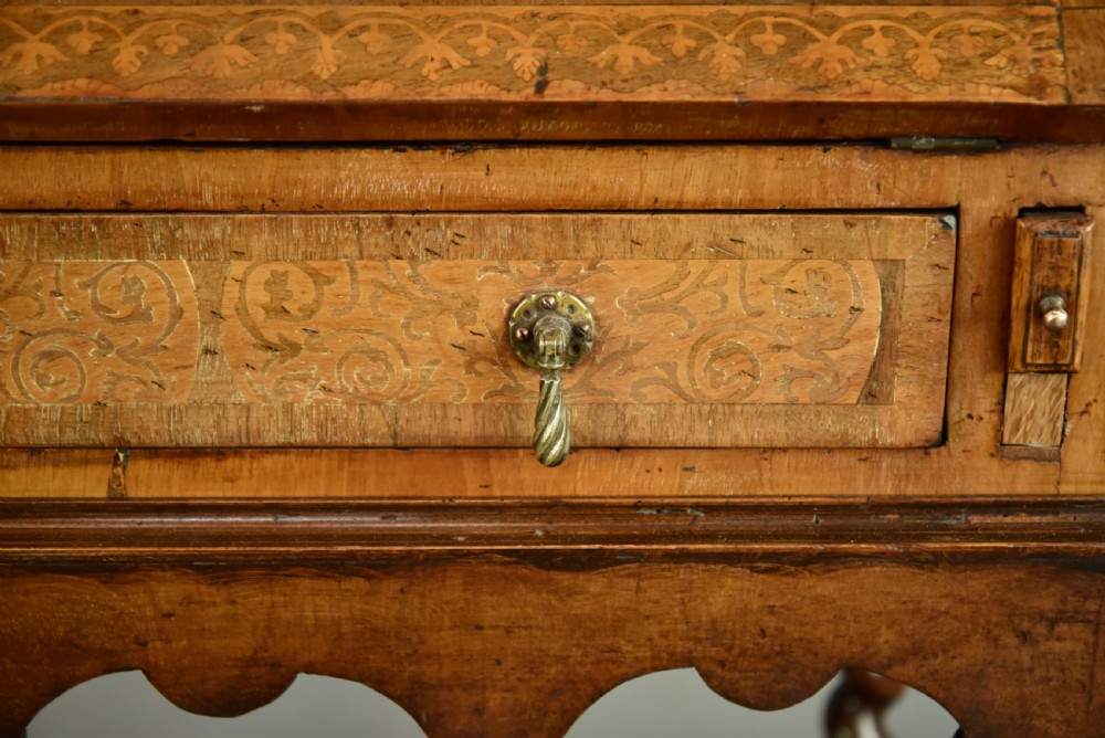 A small walnut bureau featuring an oval floral marquetry panel on the sloped front, set above a drawer and supported by four barley twist legs. View IX