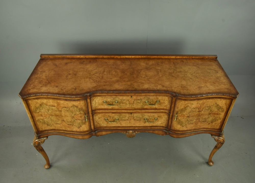 A Queen Anne style burr walnut sideboard featuring central drawers, flanking cupboard doors, carved shell detail, and cabriole legs. View II