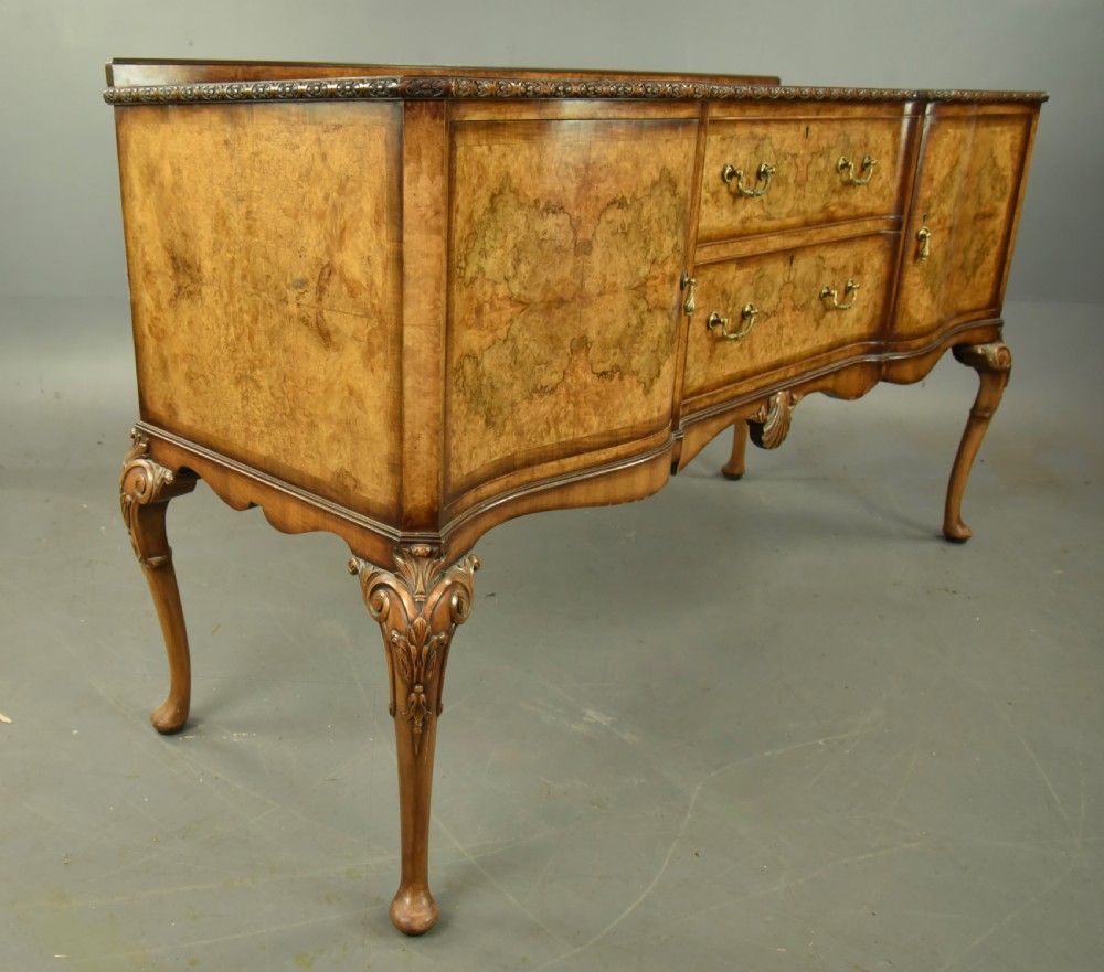 A Queen Anne style burr walnut sideboard featuring central drawers, flanking cupboard doors, carved shell detail, and cabriole legs. View III