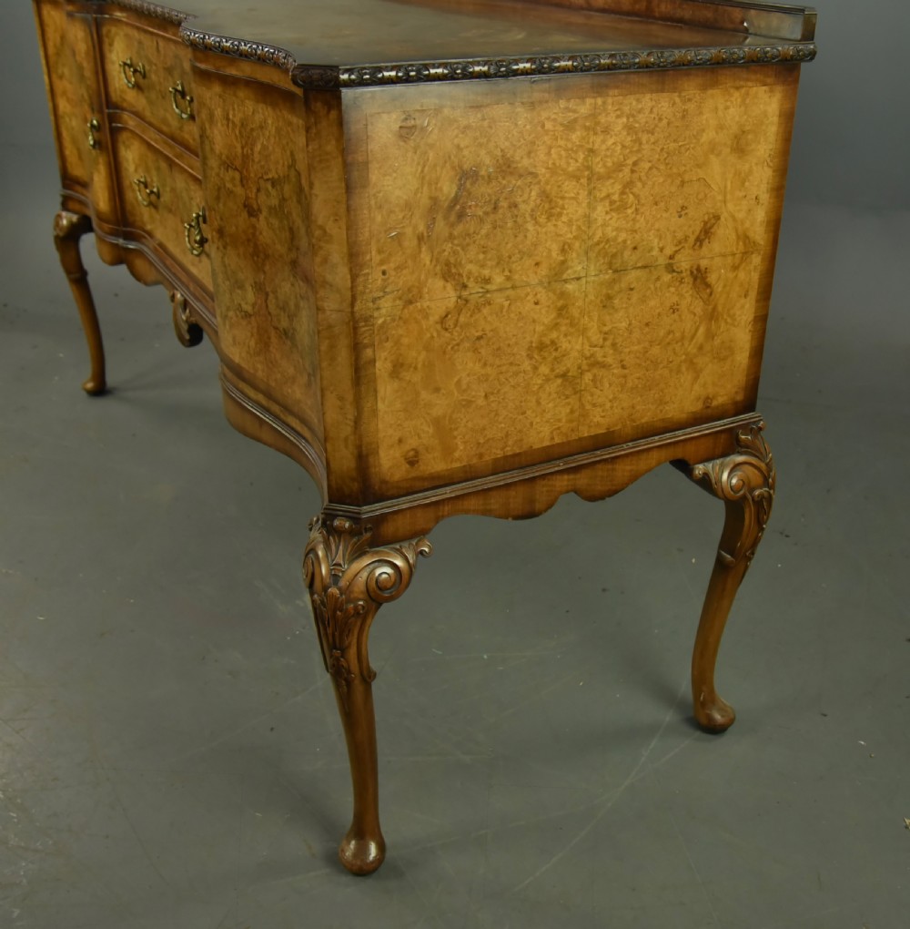 A Queen Anne style burr walnut sideboard featuring central drawers, flanking cupboard doors, carved shell detail, and cabriole legs. View IV