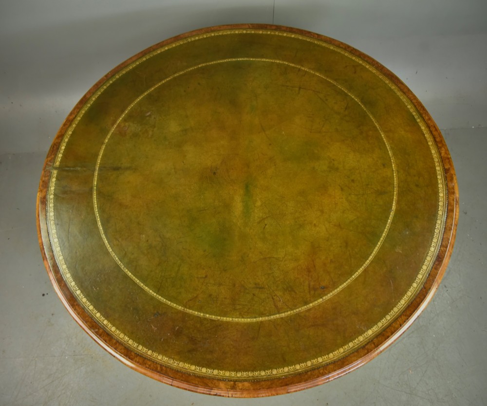 A large 19th-century circular Victorian walnut centre table featuring a green gilt-tooled leather inset writing surface and a carved pedestal base with four scroll legs on castors. View III