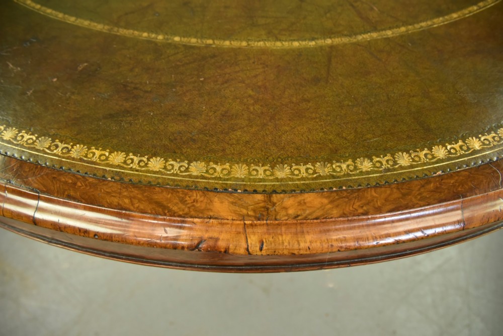 A large 19th-century circular Victorian walnut centre table featuring a green gilt-tooled leather inset writing surface and a carved pedestal base with four scroll legs on castors. View IV