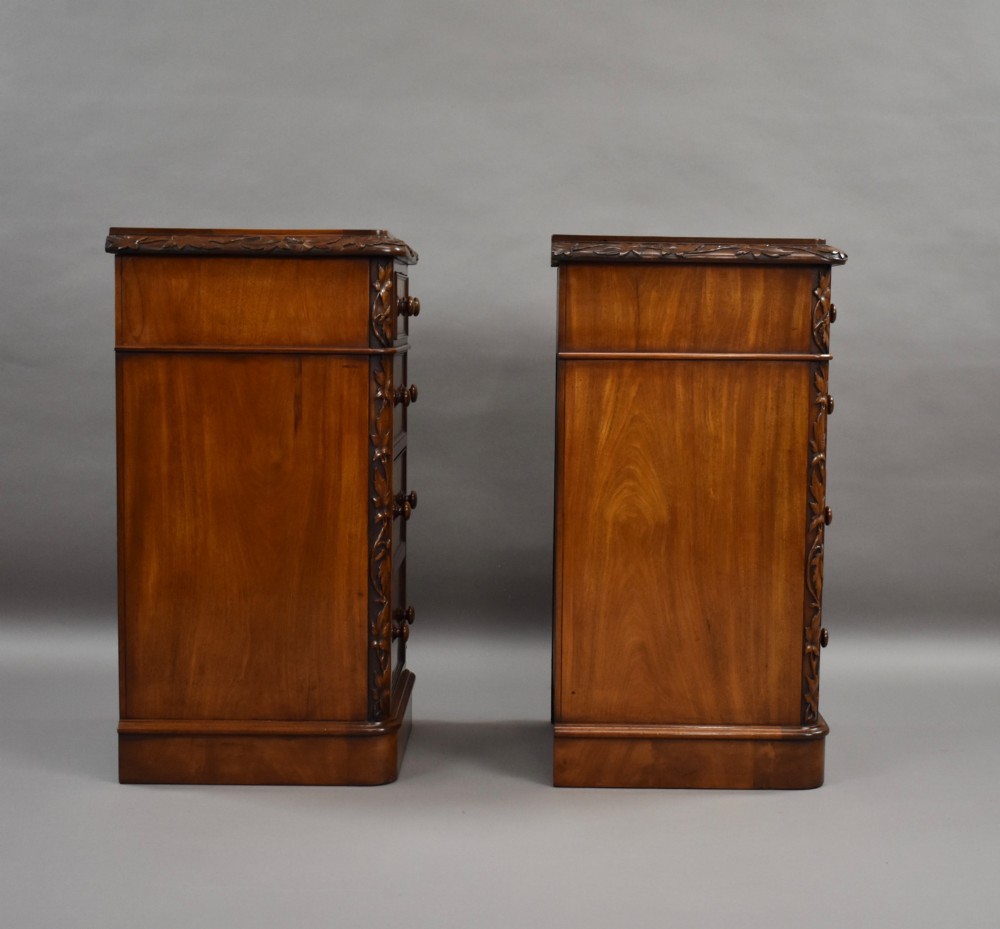 A pair of tall Victorian mahogany bedside chests with four drawers each, carved foliate columns, and turned wooden knobs on plinth bases. View V