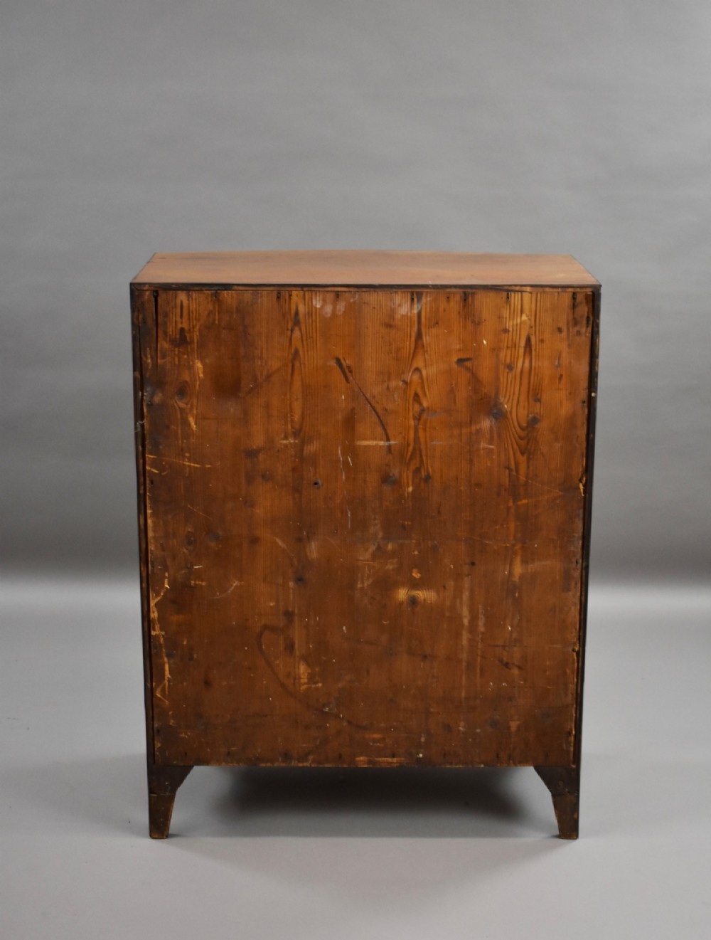 A narrow Regency mahogany bowfront chest featuring two short over three long drawers with turned brass handles and splayed bracket feet. View VIII