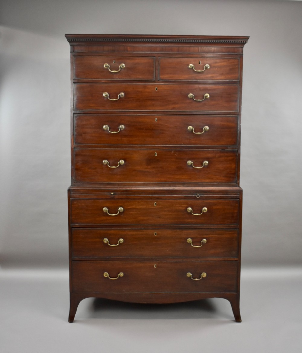 A two-section Georgian mahogany chest on chest featuring multiple drawers with brass swan-neck handles, a dentil cornice, and bracket feet.