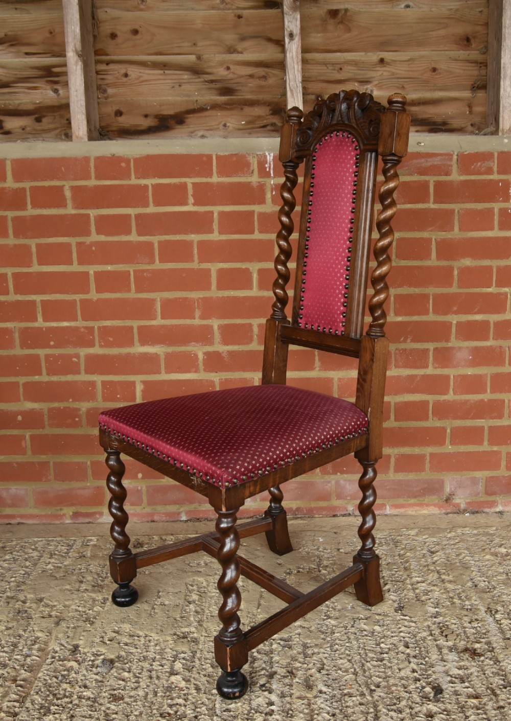 A set of eight carved oak dining chairs featuring barley twist supports, high carved crests, and red upholstered seats and backrests with brass stud detailing. View III