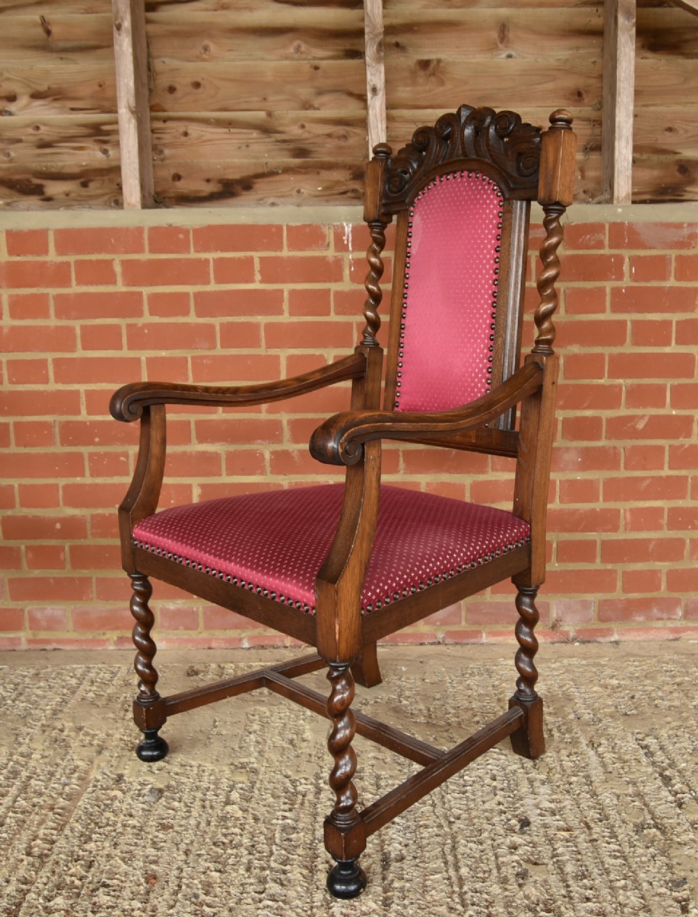 A set of eight carved oak dining chairs featuring barley twist supports, high carved crests, and red upholstered seats and backrests with brass stud detailing. View VI