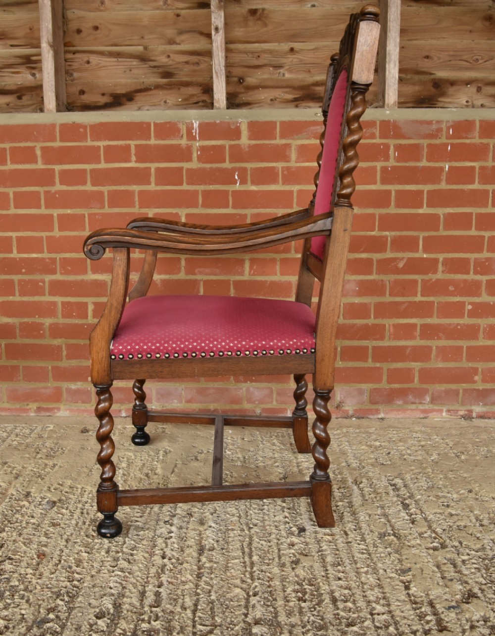 A set of eight carved oak dining chairs featuring barley twist supports, high carved crests, and red upholstered seats and backrests with brass stud detailing. View VII