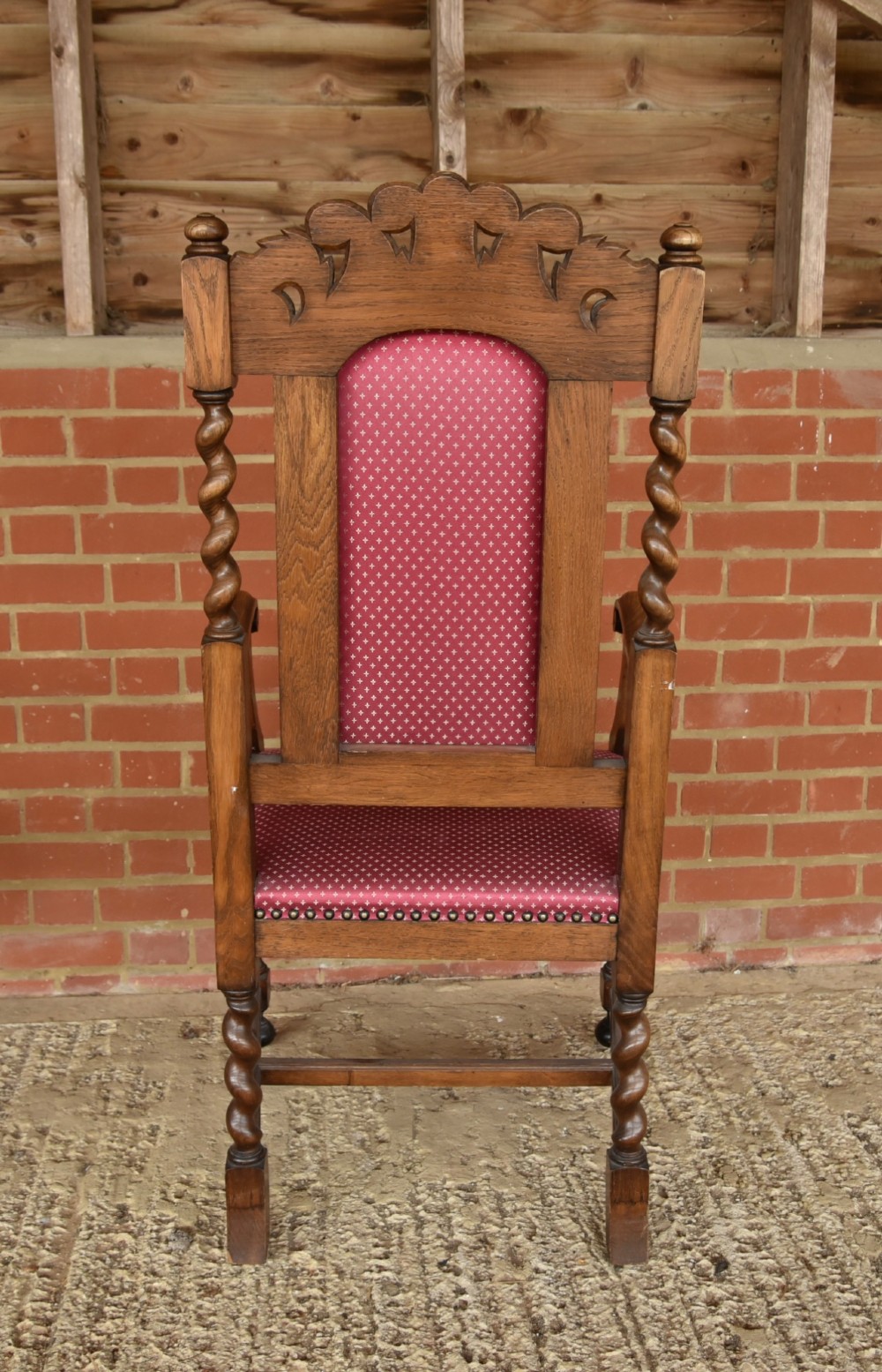 A set of eight carved oak dining chairs featuring barley twist supports, high carved crests, and red upholstered seats and backrests with brass stud detailing. View VIII