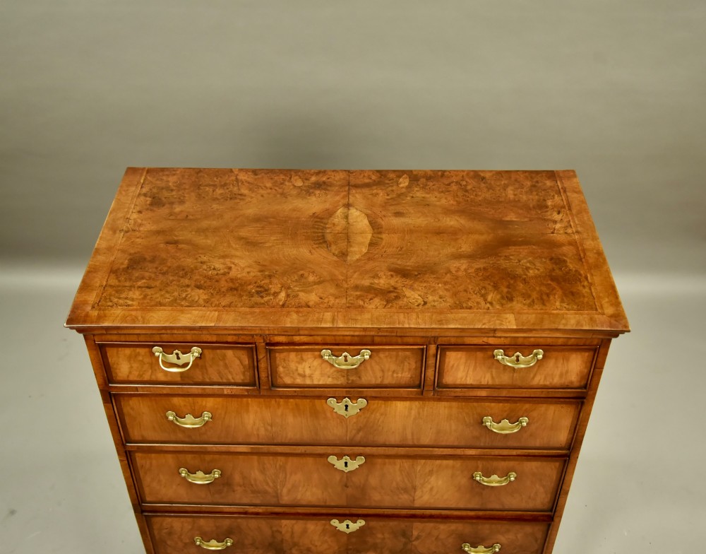 An 18th-century Georgian walnut chest of drawers featuring three short drawers over three long graduated drawers with brass handles and bracket feet. View III