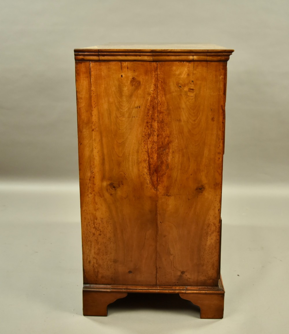 An 18th-century Georgian walnut chest of drawers featuring three short drawers over three long graduated drawers with brass handles and bracket feet. View V