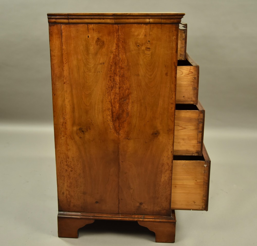 An 18th-century Georgian walnut chest of drawers featuring three short drawers over three long graduated drawers with brass handles and bracket feet. View VI