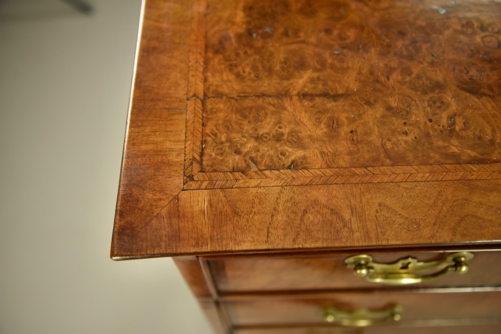 An 18th-century Georgian walnut chest of drawers featuring three short drawers over three long graduated drawers with brass handles and bracket feet. View VII