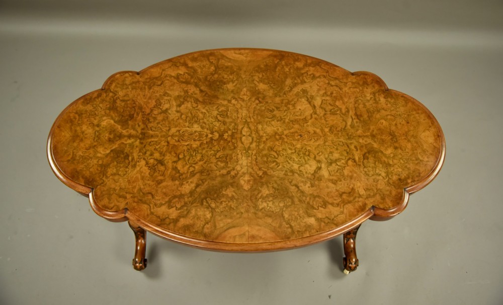 A Victorian burr walnut low coffee table featuring a shaped serpentine top, turned stretcher base, and inlaid legs on brass castors. View III