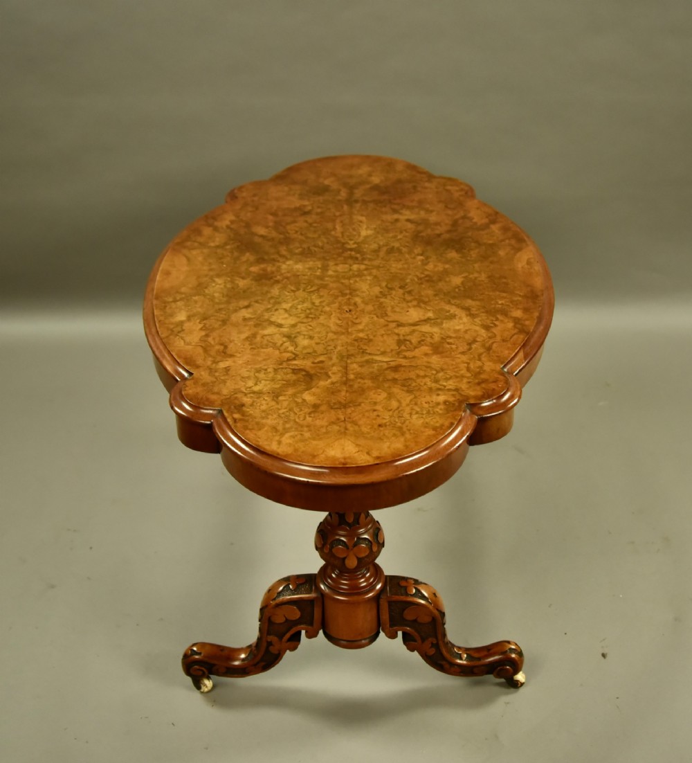 A Victorian burr walnut low coffee table featuring a shaped serpentine top, turned stretcher base, and inlaid legs on brass castors. View IV