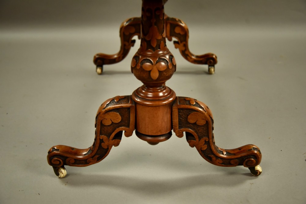 A Victorian burr walnut low coffee table featuring a shaped serpentine top, turned stretcher base, and inlaid legs on brass castors. View V