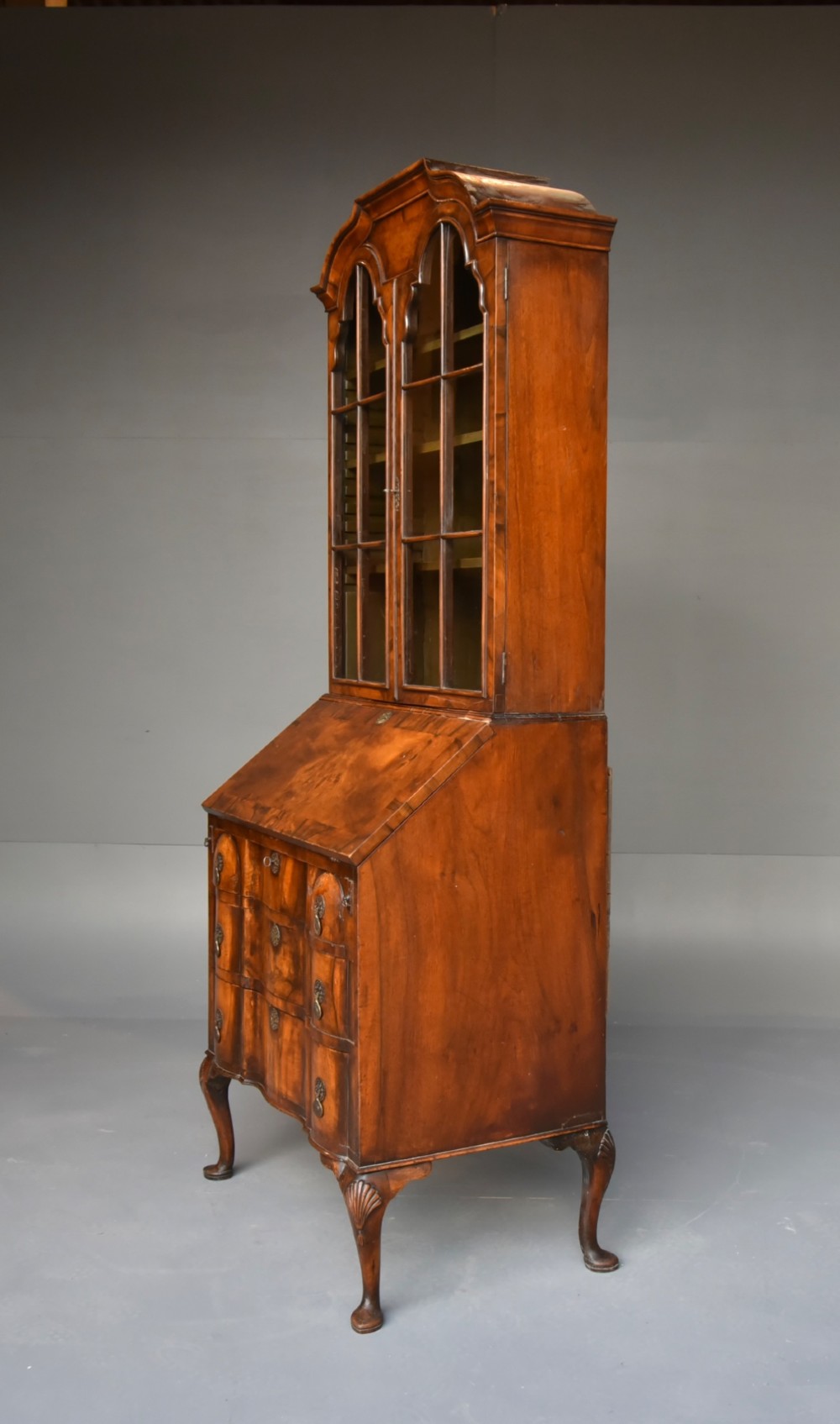 An antique Queen Anne style bureau bookcase in warm walnut featuring a double-domed glazed top section above a slant-front bureau and three drawers on cabriole legs. View II