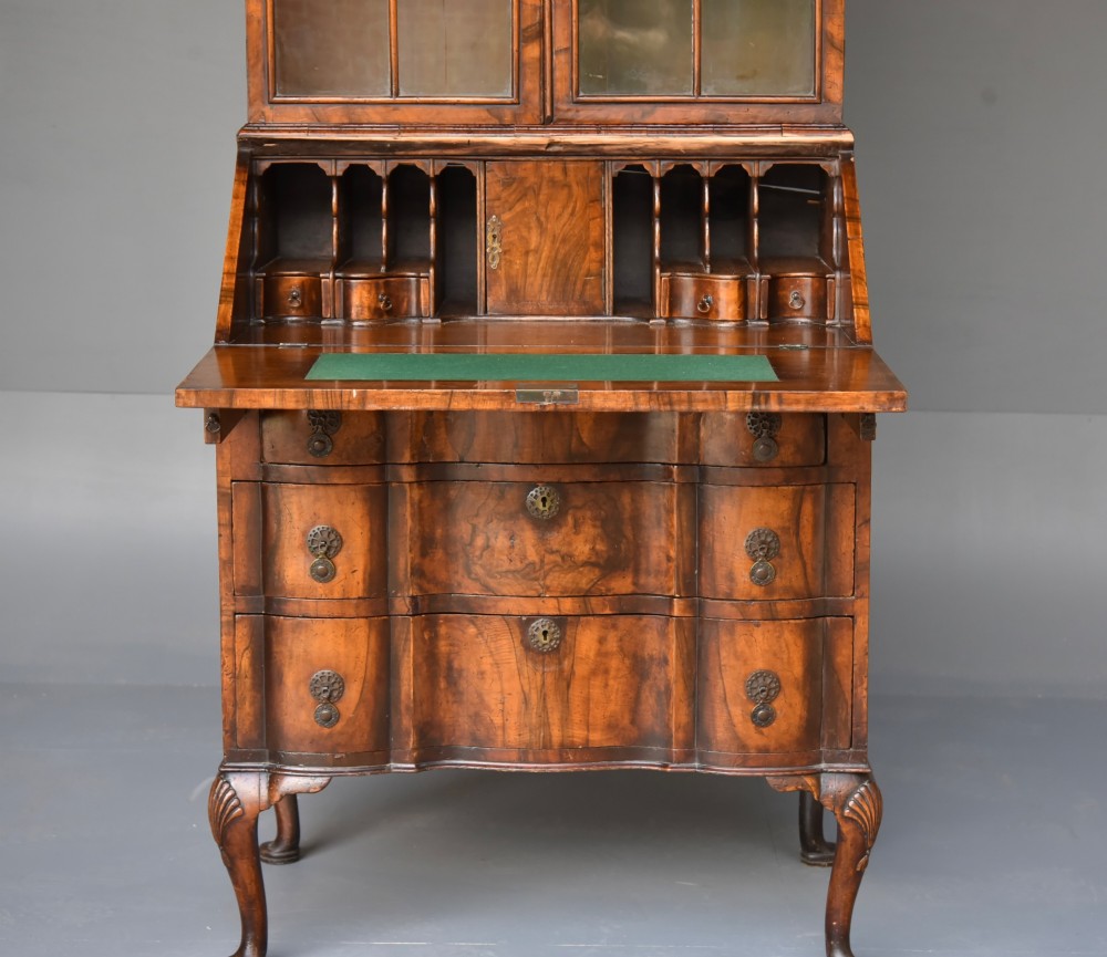 An antique Queen Anne style bureau bookcase in warm walnut featuring a double-domed glazed top section above a slant-front bureau and three drawers on cabriole legs. View VI