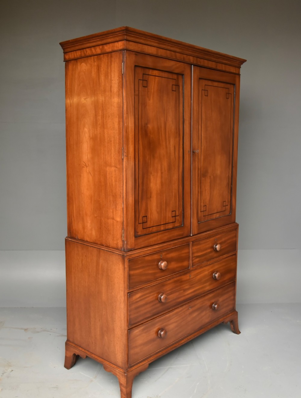 A Georgian mahogany gentlemans wardrobe featuring a two-door upper section with ebony line inlay over a base of two short and two long drawers on bracket feet. View III