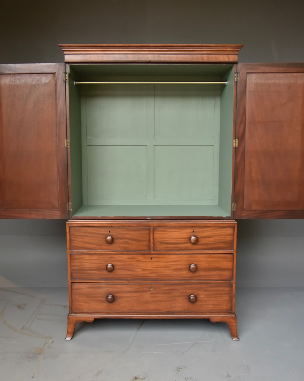 A Georgian mahogany gentlemans wardrobe featuring a two-door upper section with ebony line inlay over a base of two short and two long drawers on bracket feet. View IV