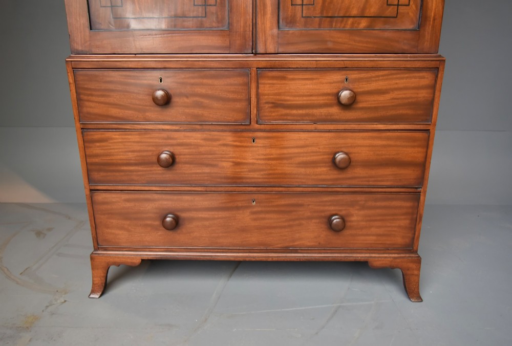 A Georgian mahogany gentlemans wardrobe featuring a two-door upper section with ebony line inlay over a base of two short and two long drawers on bracket feet. View VI