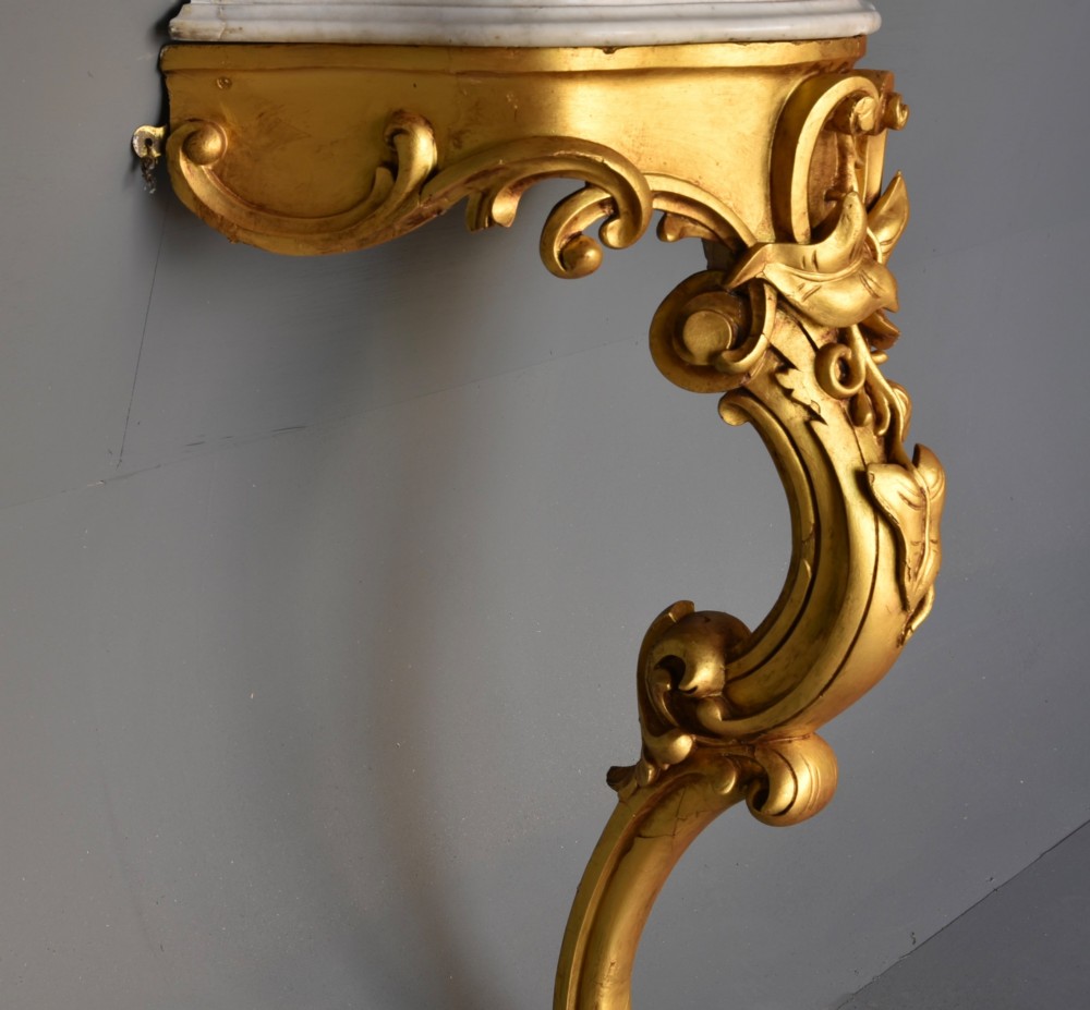 A 19th-century Rococo Revival wall-mounted giltwood console table with a single carved support leg featuring acanthus leaf scrolls and a shaped white marble top. View III
