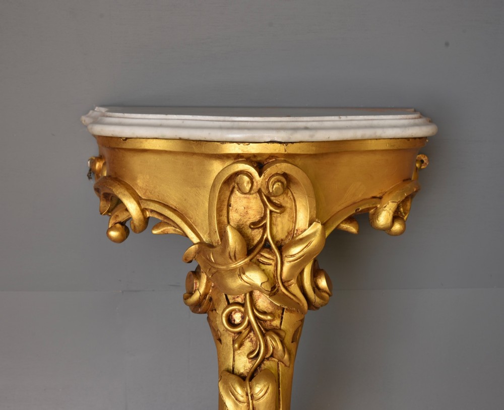 A 19th-century Rococo Revival wall-mounted giltwood console table with a single carved support leg featuring acanthus leaf scrolls and a shaped white marble top. View V