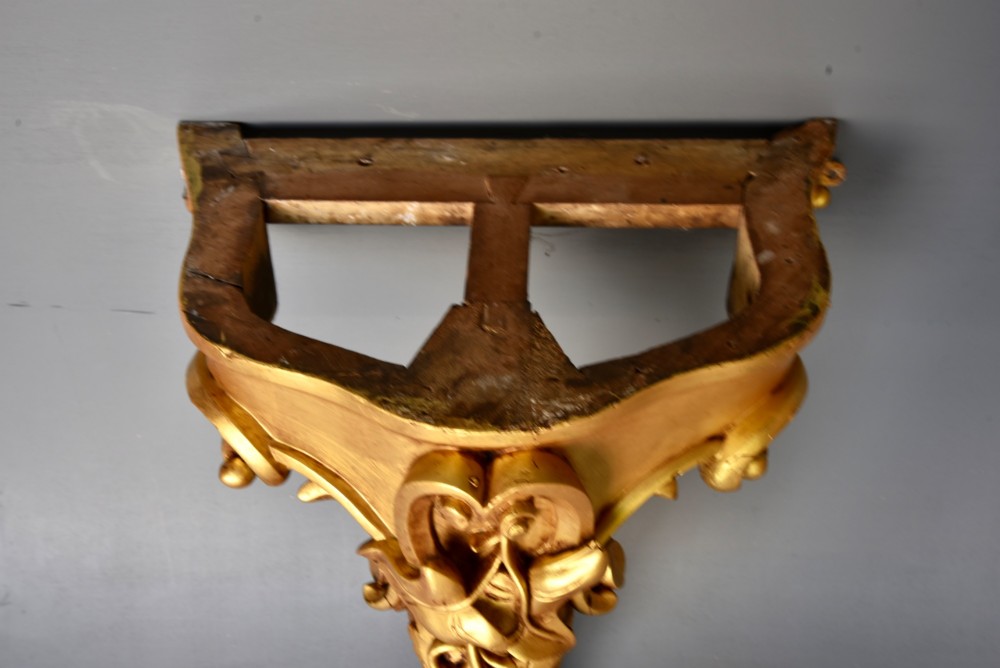 A 19th-century Rococo Revival wall-mounted giltwood console table with a single carved support leg featuring acanthus leaf scrolls and a shaped white marble top. View VII