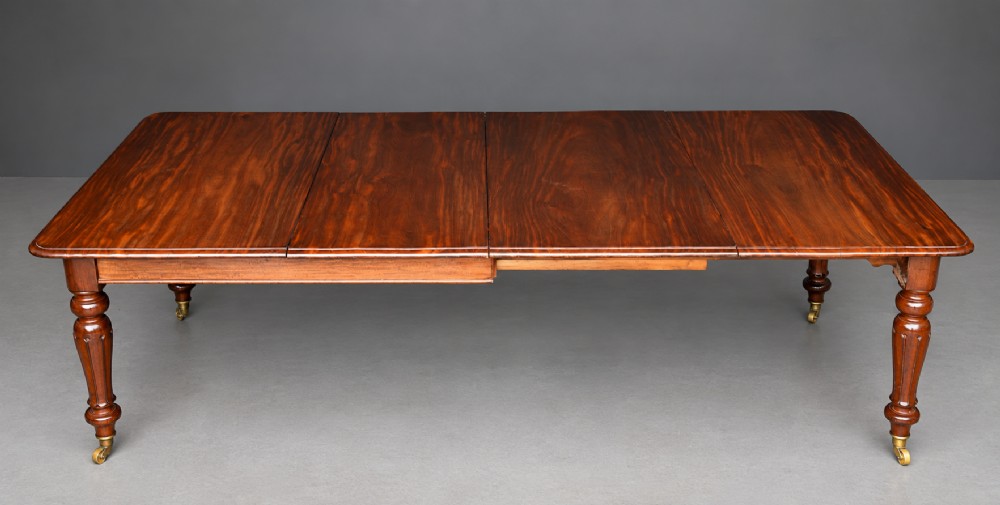 A Victorian mahogany extending dining table with turned legs resting on brass castors and an expanding rectangular top.