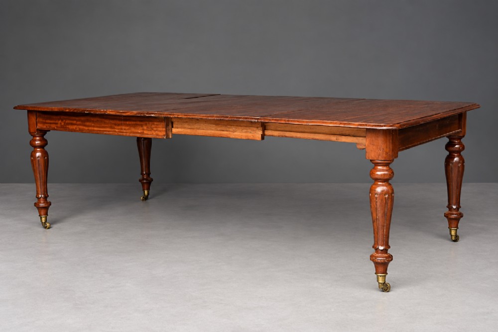 A Victorian mahogany extending dining table with turned legs resting on brass castors and an expanding rectangular top. View III