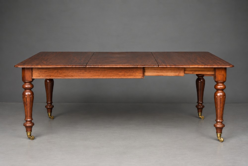 A Victorian mahogany extending dining table with turned legs resting on brass castors and an expanding rectangular top. View IV