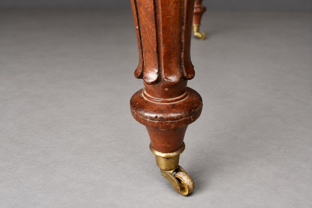 A Victorian mahogany extending dining table with turned legs resting on brass castors and an expanding rectangular top. View VI