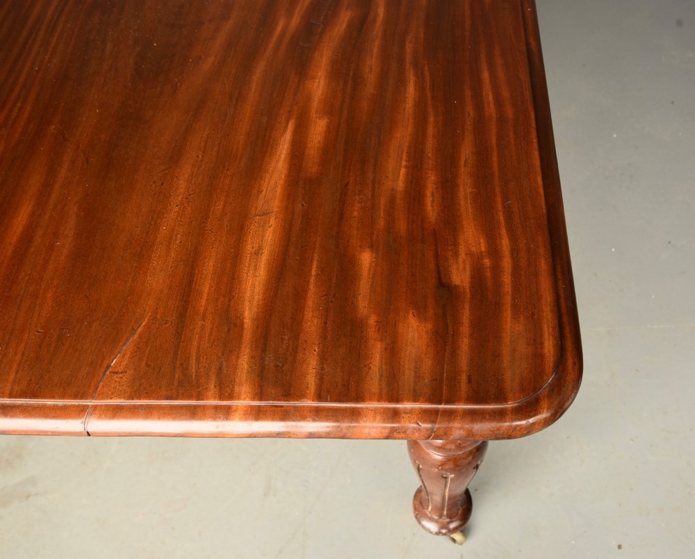 A Victorian mahogany extending dining table with turned legs resting on brass castors and an expanding rectangular top. View VII