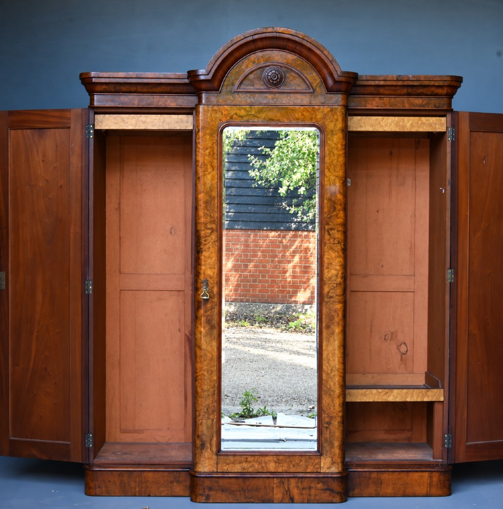 A Victorian burr walnut triple wardrobe featuring an arched central mirrored door flanked by two panelled timber doors with carved mouldings. View II